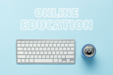 Keyboard and tin can with a drink, energy drink on a blue background. Text Online Education. The...