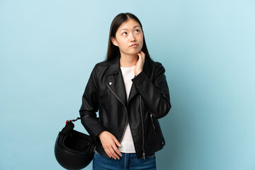 Chinese woman holding a motorcycle helmet over isolated blue background thinking an idea