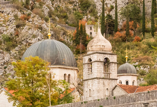 Onion-domed Orthodox Churches with Gold Latin crosses on top with another church on hillside within walled city of Kotor, Montenegro in Europe.