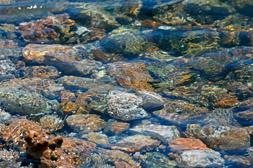 Fototapeta na wymiar crystal sea water and colourful stones on the beach. sunny day. selective focus