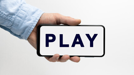 Man's hand holding a smartphone horizontally with text PLAY on white background