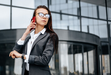 A business woman checks the time in the city during a working day waiting for a meeting. Discipline and timing. An employee goes towards a corporate meeting.