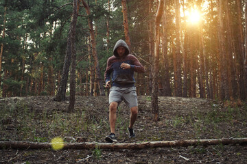 Man is engaged in running with obstacles in a pine forest. A beautiful play of light. Concept of...