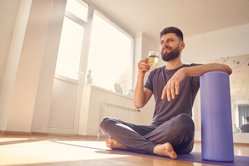 Bearded young man drinking herbal tea in yoga studio