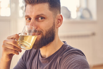 Handsome young man with beard drinking herbal tea