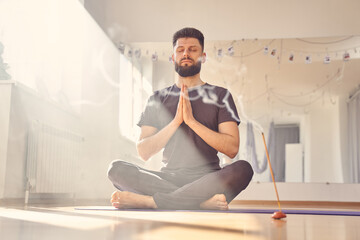 Serene young man meditating in yoga studio