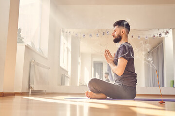 Handsome young man meditating in lotus position