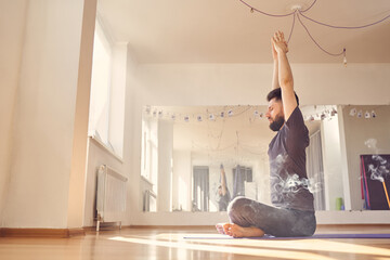 Bearded young man doing yoga exercise in studio