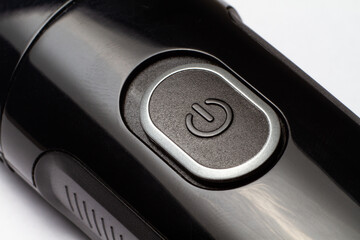 The button is on and off on a black electric razor trimmer on a white background
