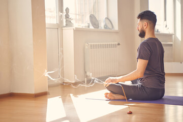 Fototapeta na wymiar Bearded young man meditating in yoga position