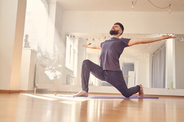 Fototapeta premium Handsome bearded man in shirt doing yoga exercise