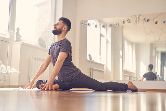 Handsome young man doing seated pigeon yoga pose