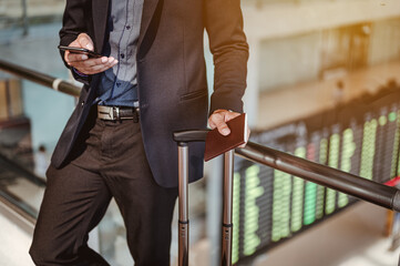 Businessman moving to terminal gate by escalator for check in boarding with luggage at the airport.