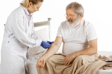 Elderly old man recovering in a hospital bed isolated on white background. Getting care. Concept of...