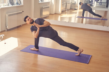 Handsome bearded man doing prayer twist pose