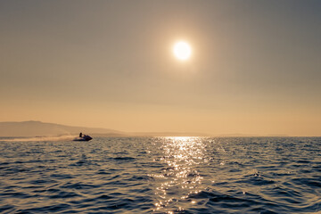 man rides a jet ski in the sea at sunset