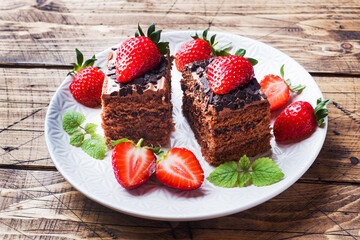Chocolate truffle cake with strawberries and mint. Wooden table.