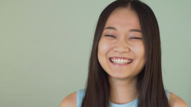 portrait close-up. cute asian girl looking at the camera and laughing sincerely 4K
