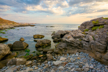 Fototapeta na wymiar sea beach with pebbles and rocks. beautiful landscape with clouds on the sky at sunrise. wide panoramic view of a bay