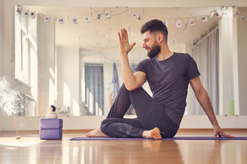 Bearded young man doing half lord of the fishes yoga pose