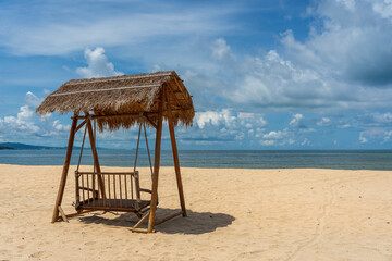 Wooden swing under a thatched roof on a sandy tropical beach near sea on island of Phu Quoc, Vietnam. Travel and nature concept