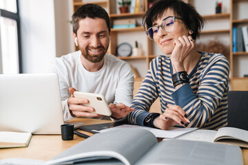 Photo of young colleges discussing project while working in office