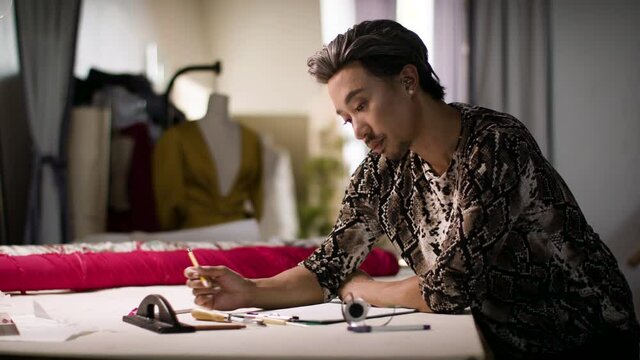 Authentic fashion designer sketching for future project in small business workshop. Getting back to work. Authentic and diverse creative. Shot in 4k and in slow-motion. 