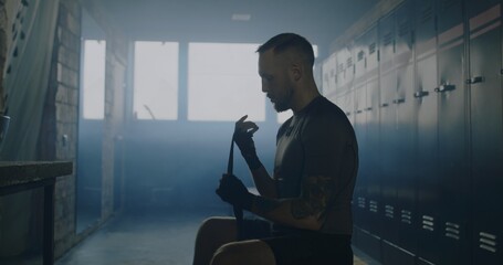 Caucasian male wraps his hands in locker room before boxing martial arts training