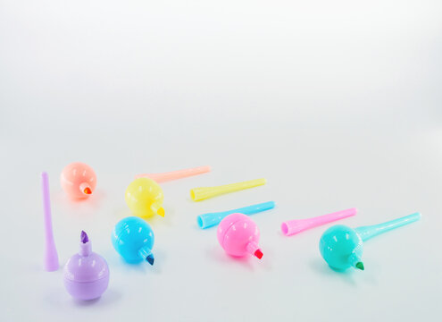Flat lay, a scattering of markers in pastel colors at the white background with place for text