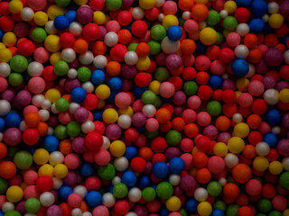 Fototapeta na wymiar Dark background texture of multicolored foam balls