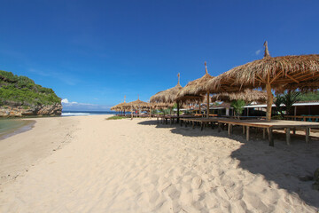 row of hut with thacthed roof at Ndrini Beach, Yogyakarta, Indonesia. tropical beach resort