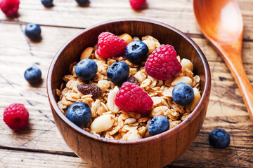 Healthy breakfast. Fresh granola, muesli with yogurt and berries on wooden background. Copy space.