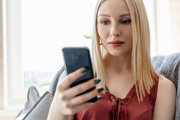 Fototapeta na wymiar Close-up portrait of a blonde girl with a smartphone indoors