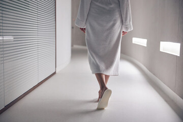 Female in a bathrobe moving along the hallway