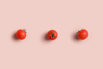 three fresh raw red tomatoes on pink background lay out horizontal by line