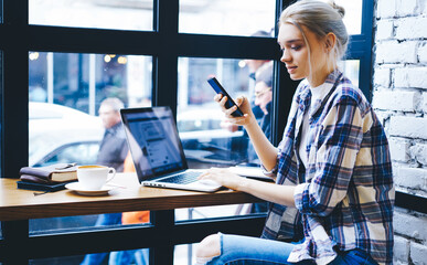 Pensive skilled female copywriter checking work of application updating software on digital...