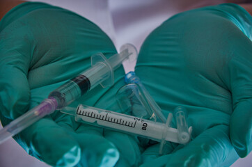The hands of the medical worker in rubber gloves hold the medicine tablet ampoules and syringes injections.