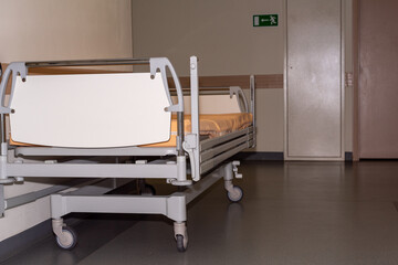 Interior of a hospital. An empty bed stands in the hospital hallway.
