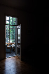 An open door with bright light streaming into a very dark room.