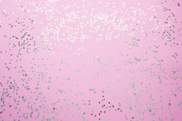 Confetti of gold stars glisten on a pink background. Festive holiday pastel backdrop.