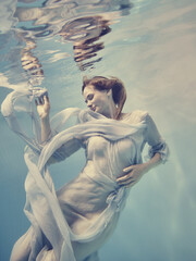 Portrait of a girl in a blue dress floating underwater