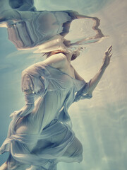 Portrait of a girl in a blue dress floating underwater