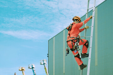 Workers climb the stairway or fixed ladder to the factory roof with safety equipment to assist with abseiling.