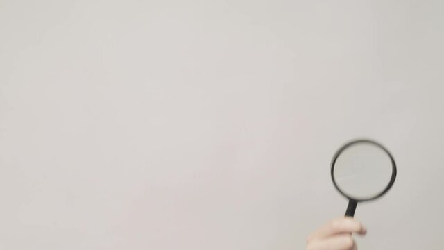 Hand gestures. Advertisement background. Woman discovering copyspace with magnifying glass isolated on gray.