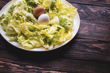 plate of lettuce with two eggs on a wooden board