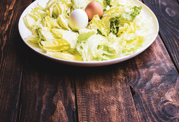 plate of lettuce with two eggs on a wooden board