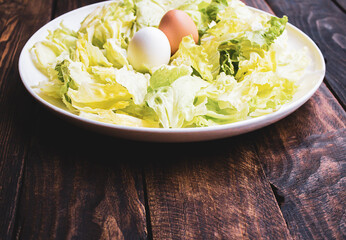 plate of lettuce with two eggs on a wooden board