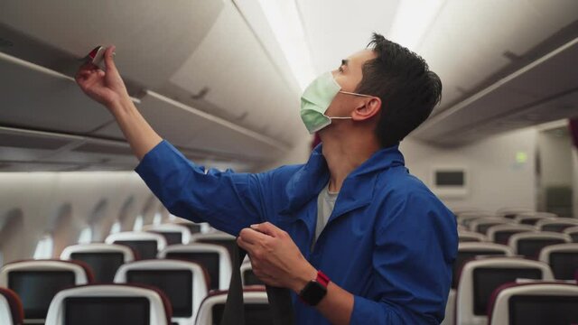 Asian man traveler wear mask, walk on airplane during covid pandemic.
