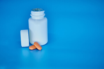 Medication bottle and orange pills on blue pastel colored background. Medication and prescription pills flat lay background. Opioid epidemic