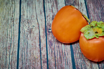 Delicious ripe persimmon fruit on wooden background